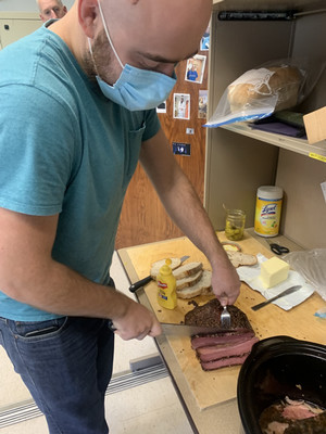 Ian cutting beef brisket while Paul watches